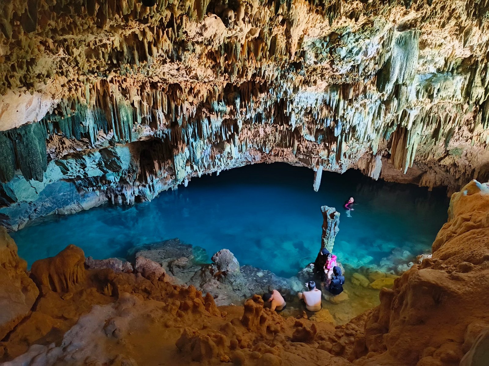 “Traveler swimming in the turquoise saltwater pool inside Rangko Cave, Labuan Bajo – a hidden blue lagoon illuminated by sunlight, captured by BajoLuxe Tour.”